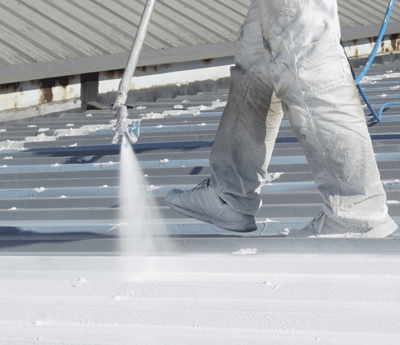 Professional performing commercial metal roof repair by applying a protective coating to ensure durability and longevity.