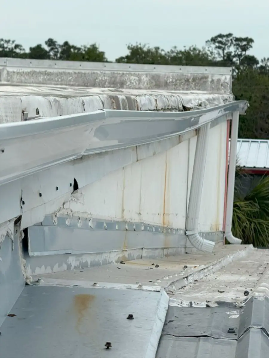 roof-leaks-after-snow-pennsylvania-featured Close-up of a low-slope commercial roof edge with visible weathering, staining, and drainage-related damage after winter conditions.