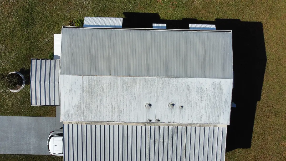 commercial-hail-damage-roof-inspection-pennsylvania-building Aerial view of a commercial roof in Pennsylvania being assessed for hail damage, showing a white coated roof and adjacent metal