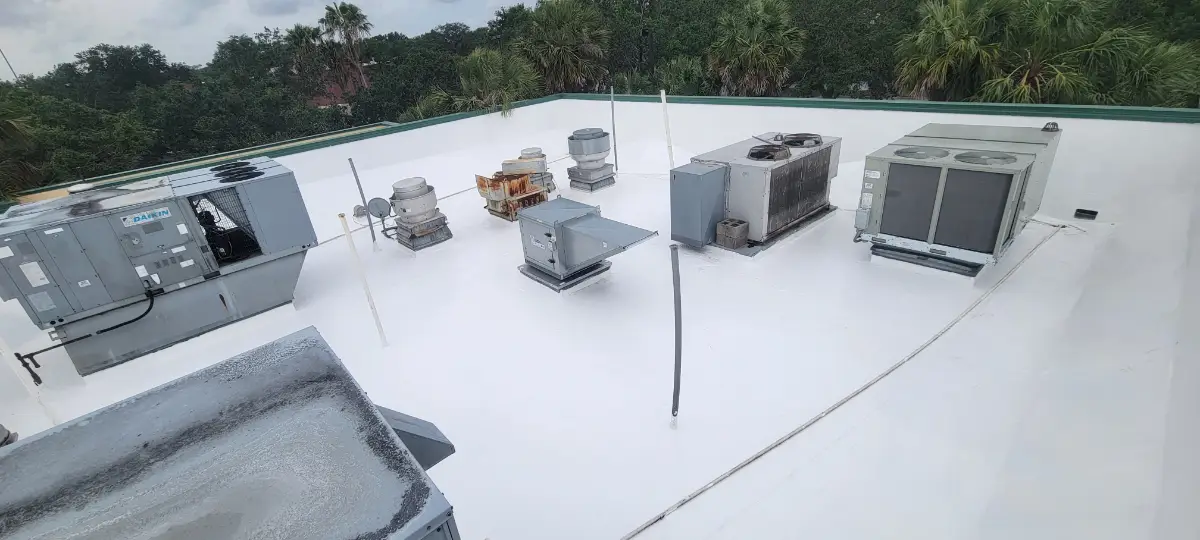 white-epdm-commercial-flat-roof White EPDM roofing membrane on a commercial flat roof with rooftop HVAC units, vents, roof penetrations, and a parapet wall